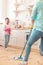 Cute beaming girl looking at her mother mopping the floor