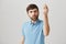 Cute bearded european male standing with raised hand and showing italian gesture and puckered lips, frowning, being
