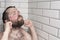 Cute bearded man standing in the bathroom shower and playfully s