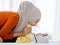 A cute and beautiful Asian Muslim in hijab dress kissing her baby daughter with a tender gesture. Love, care, and relationship