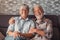 Cute and beautiful couple of old people smiling and looking at the camera having fun at home together. Portrait of seniors sitting