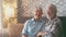 Cute and beautiful couple of old people smiling and looking at the camera having fun at home together. Portrait of seniors sitting