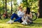 Cute beautiful couple is sitting on a green lawn in the park, their bicycles on the background. A man is touching his girlfriend`