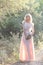 Cute beautiful girl blonde curly hair walking in the woods in a wedding dress in the sun at sunset