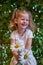 Cute beautiful girl with flower holding a big white chamomile flower. Child in nature in the grass.