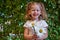 Cute beautiful girl with flower holding a big white chamomile flower. Child in nature in the grass.