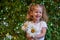 Cute beautiful girl with flower holding a big white chamomile flower. Child in nature in the grass.