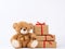 Cute beige teddy bear and stack of gifts in boxes wrapped in brown eco paper