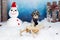 Cute Bichon Havanese dog with dark blue scarf on a vintage wooden sled in a winter?s tale decor with snow, snowman with Santa`s