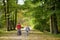 Cute big sisters walking in a park with baby brother in pushchair. Siblings walk in city park. Girls pushing a stroller for infant