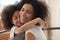 Cute biracial daughter hug smiling young mom