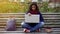 Cute biracial girl carried away by exciting research project, sitting in park