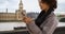 Cute black female in her 20s texts on mobile device near Big Ben clock tower