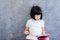 Cute black hair little girl reading book by the wall