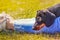 Cute black and tan miniature Dachshund puppy lying with his head on the legs of a lady with light blue frayed cropped jeans