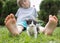 Cute black and white kitten sits between the little bare feet of a child on the lawn on sunny summer day
