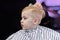 Cute blond baby boy in a barber shop having haircut by hairdresser. Hands of stylist with hairbrush. Children fashion.