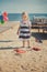 Cute blond baby girl child posing enjoying summer life time on sandy beach sea side on wooden pier with colourful plenty balloons