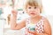 Cute blond baby girl eats ice cream and fruits
