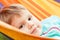 Cute blond baby girl lying in striped hammock