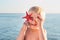 Cute blond boy holds starfish and seashell and smiling. Kid on sea background