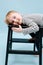 Cute blond boy lying on a stepping stool, relaxing Over blue background