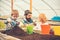 Cute blond boy playing gardening spade and colorful pots and making big mound. Bearded man with magnifying glass