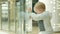 A cute blond boy of two years is considering a store through the glass. The kid carefully examines the inside of the