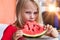 Cute blond child with watermelon indoors. Pretty little toddler girl 4 year eating watermelon close-up at home