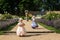 Cute blond curly twin girls dressed up as princesses in the garden of ancient castle, beautiful small girls in blue and pink long