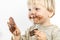 Cute blond dirty toddler eating chocolate bar with great pleasure