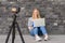 Cute blond female blogger with laptop recording video