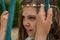 Cute blond girl with clear eyes on a swing with a wreath of white flowers on her head