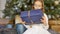 Cute blond girl has recieved a gift box wrapped in craft dark blue paper sitting near christmas tree, happy childhood