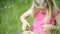 Cute blond girl in preschool age sitting in green grass playing with smart phone