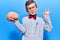 Cute blond kid wearing nerd bow tie and glasses holding brain doing ok sign with fingers, smiling friendly gesturing excellent