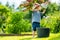 Cute blond toddler playing with a cooking pot outdoors in the garden. Kid helping parents with gardening in the backyard in bright