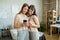 Cute blond twin sisters scrolling through photos in smartphone