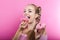 Cute blond woman eating pink frosted donuts