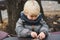 Cute blonde boy playing with toys outdoors. Happy and healthy childhood. Baby boy on a walk in cold autumn day