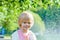 Cute blonde caucasian girl with sprinklers at the park. Summer vacation happy childhood