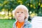 Cute blonde caucasian sad kid sitting on the bench at the park. Stress. emotion, depression