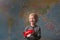 A cute blonde child holds a red plane of a world map