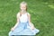 Cute blonde child practicing yoga on the grass outdoors