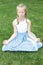 Cute blonde child practicing yoga on the grass outdoors