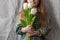 Cute blonde girl with a bouquet of white tulips in hands faceless. Mothers day, spring concept.Pretty toddler in a dress