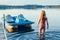 Cute blonde girl walking to pedal boat in lake water on sunset. Summer sport water outdoors activity. Real authentic happy