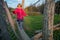 Cute blonde girl walking on a wooden bridge at playground.