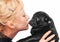 Cute blonde kissing a black pug puppy