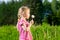 Cute blonde little girl blowing a dandelion and making wish